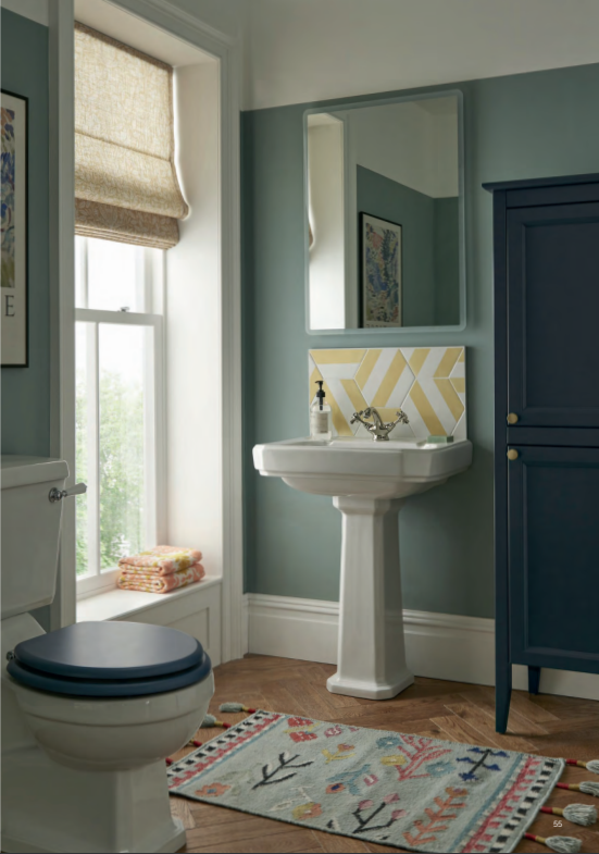 Klassieke badkamer met wastafel op zuil, spiegel en donkerblauw meubel